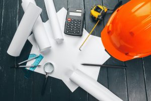 Engineer workplace with blueprints, compass, pencil and safety helmet