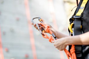 Close-up of safety equipment for climbers weared on the woman with climbing wall on the background